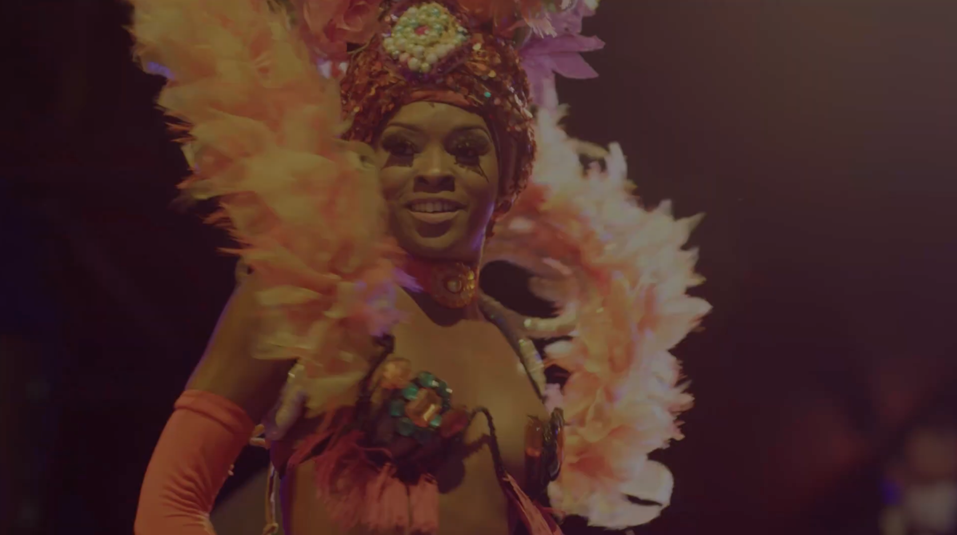 A Tropicana showgirl in a flaming feathered headdress smiles from the stage in Havana, Cuba